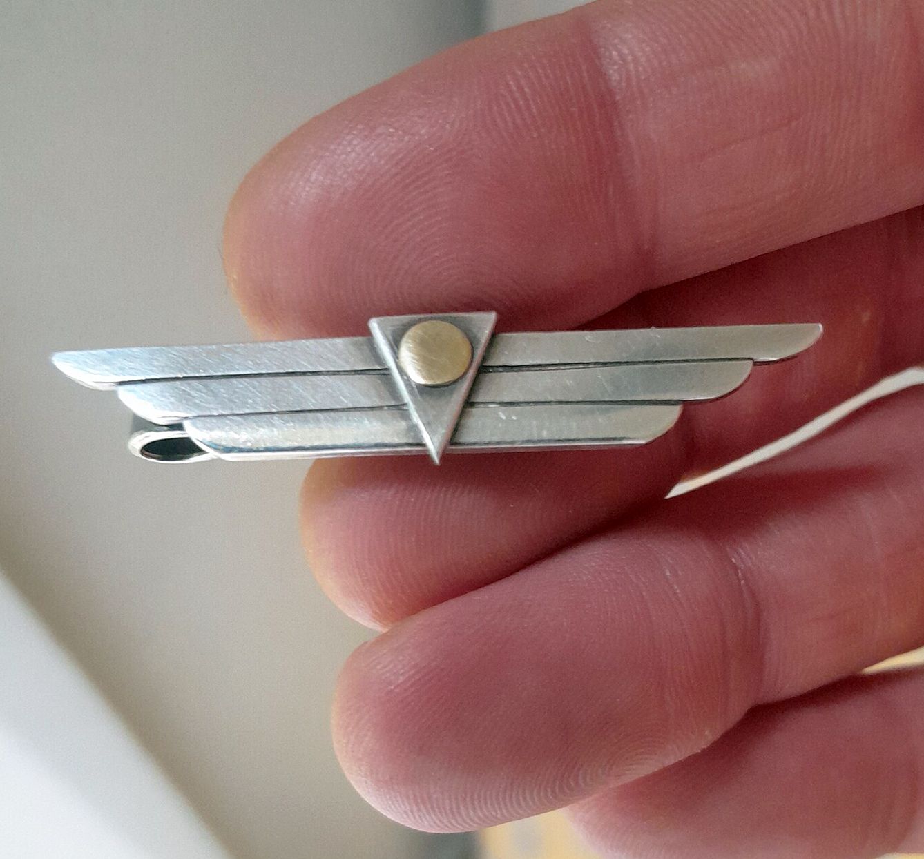 Tie clip in hand for scale
