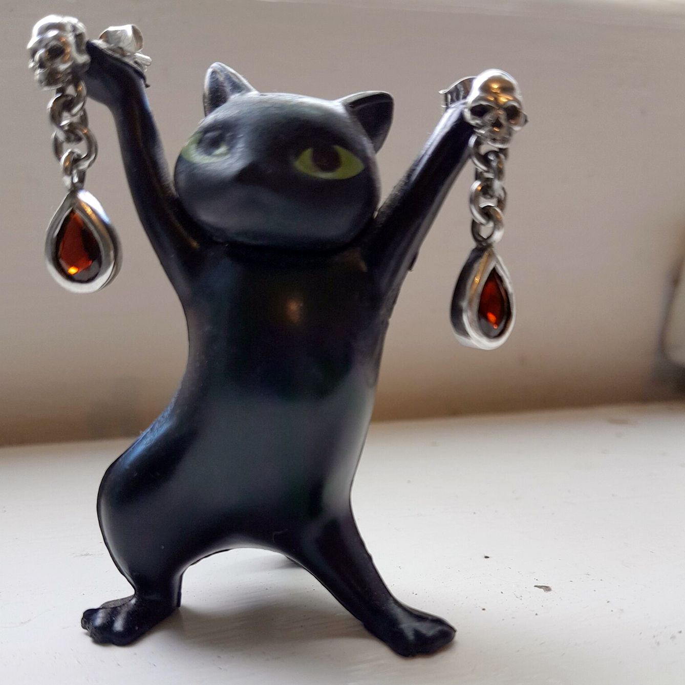 Small toy cat holds earrings