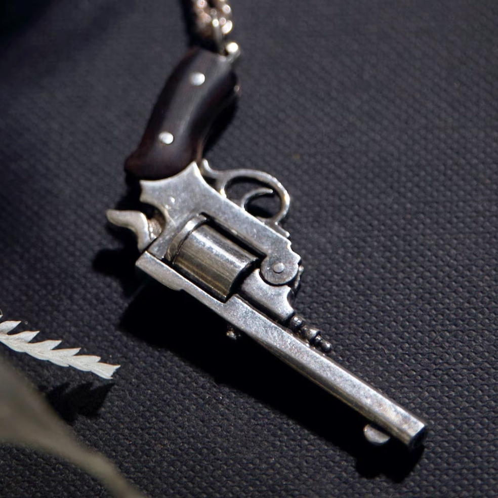 Sterling silver western revolver necklace. Revolver has moving cylinder and hammer with black buffalo horn handle.